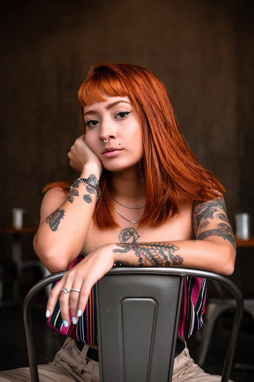 Red Headed Woman Sitting in Chair With Tattoos